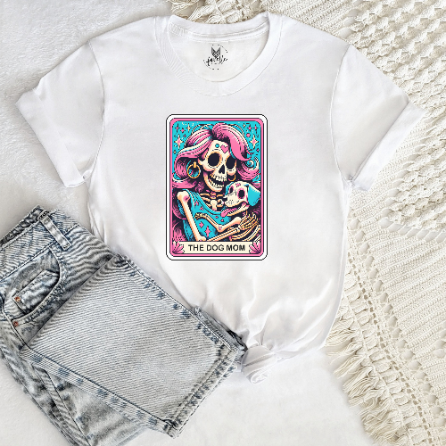 White t-shirt with a colorful graphic of a skeleton and text 'The Dog Mom' on a textured surface.