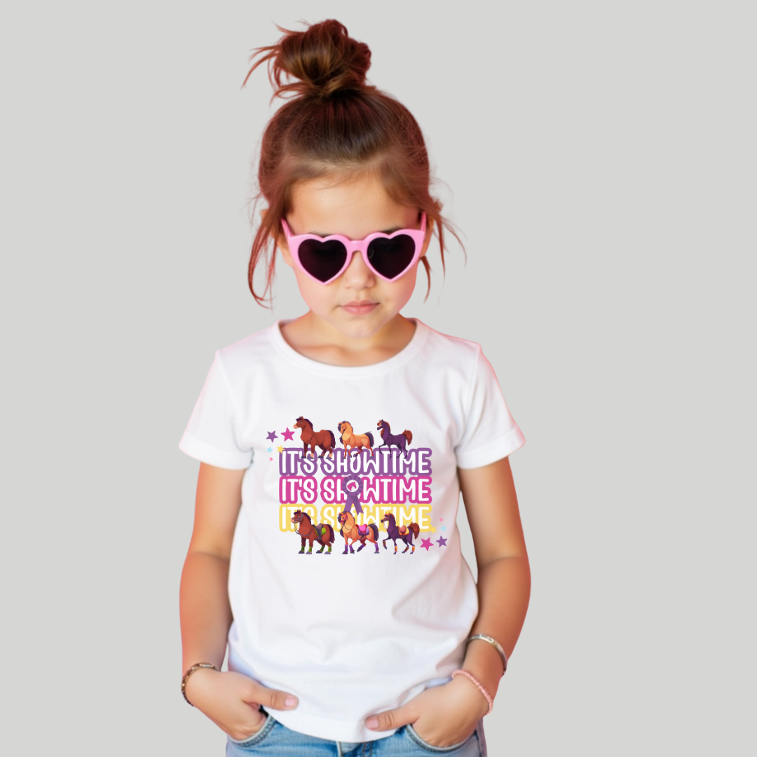 Child wearing a white t-shirt with colorful text and horse graphics, paired with pink heart sunglasses on a light gray background.