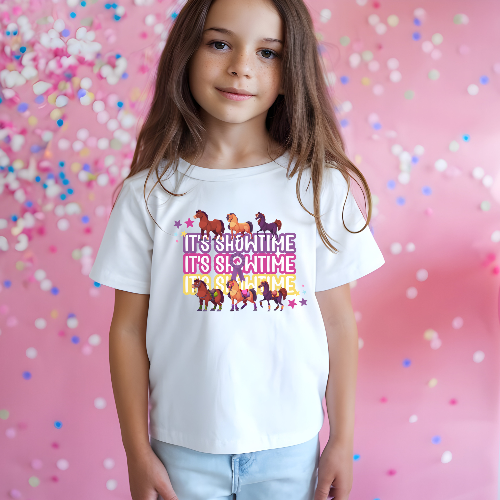 Girl wearing a white t-shirt with colorful text and horse graphics on a pink background with confetti.