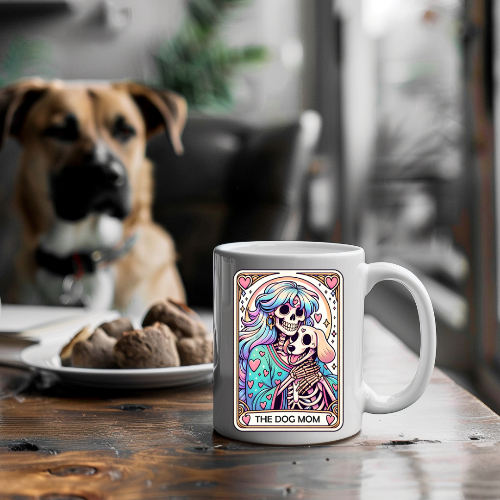 Mug with colorful design and text 'The Dog Mom' on a wooden table with a dog in the background.