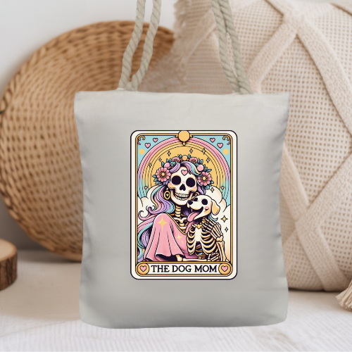 Tote bag with a colorful design of a skeleton holding a dog, labeled 'The Dog Mom', against a neutral background.